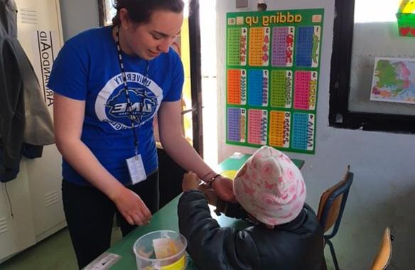 A U N E student helps a child